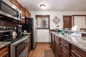 A kitchen with stainless steel appliances, wooden cabinets, a granite countertop, and a window with blinds. - Walk to Mtn/Bus+Pool-HotTub-Grill-W/D (Steamboat Springs)