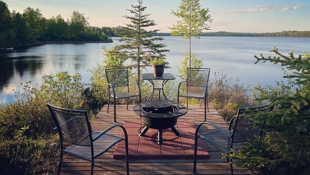 A deck with outdoor seating and a fire pit overlooking a lake. - DENALI PENTHOUSE, lakefront near Talkeetna and Denali State Park  (Trapper Creek)