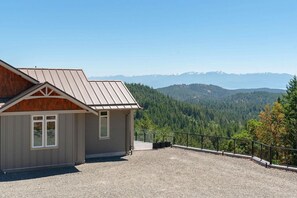 Ein Gebäude mit einem geneigten Dach, einer Schotterauffahrt und Blick auf einen bewaldeten Gebirgszug.