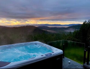 Ein Whirlpool auf einem Balkon mit Blick auf ein bewaldetes Tal und Berge.