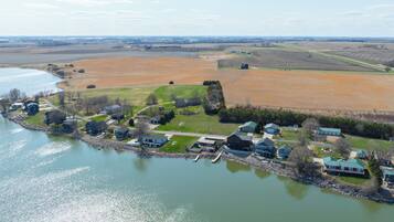 Vista aérea de una propiedad junto al lago con casas, un muelle y campos circundantes.