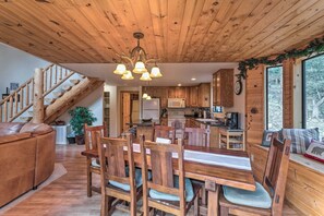 A wooden interior with a dining area, kitchen, and staircase.