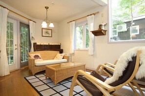 A room with a wicker sofa, a glass coffee table, a wooden chair, and a view of the outdoors. - Ricky House Hakuba (Hakuba)