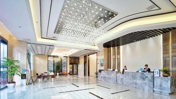 A modern hotel lobby with a marble reception desk, seating area, and a decorative ceiling light fixture. - Greentree Inn Changzhou Jintan District Xerbu Town East Salt Lake City Business Hotel (Changzhou)
