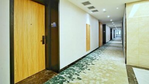 A long, narrow hotel corridor with wooden doors, a patterned carpet, and a tiled floor. - Greentree Inn Changzhou Jintan District Xerbu Town East Salt Lake City Business Hotel (Changzhou)