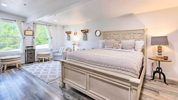 A bedroom with a large bed, bedside tables, a nightstand, and a window with curtains. - 'Hilltop Hideaway' Branson Home w/ Trampoline! (Branson)