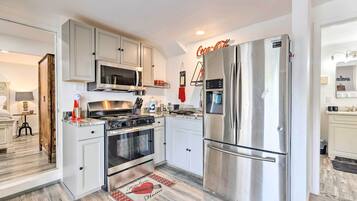 Una cocina moderna con electrodomésticos de acero inoxidable, armarios blancos y un tapete con estampado rojo y blanco.