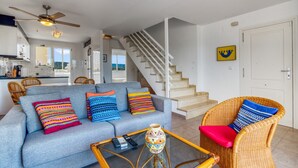 Een woonkamer met een bank, stoelen, een salontafel en een trap.