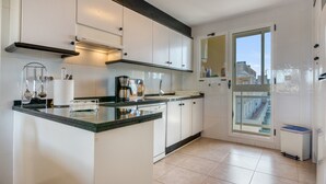 Een moderne keuken met witte kasten, een groot schiereiland en een uitzicht door een glazen deur.