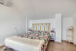 A bedroom with a bed, bedside tables, a nightstand, a lamp, and a shelf.
