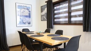 Ein Konferenzraum mit einem Holztisch, schwarzen Stühlen und zwei Postern an der Wand.