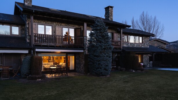Une maison en pierre à deux étages, dotée d’un balcon, d’un coin repas et d’une cheminée.