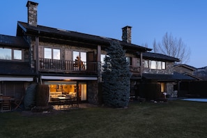 A two-story stone house with a balcony, a dining area, and a fireplace.