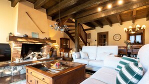 Un salon chaleureux avec une cheminée, un canapé, une table basse et un lustre.
