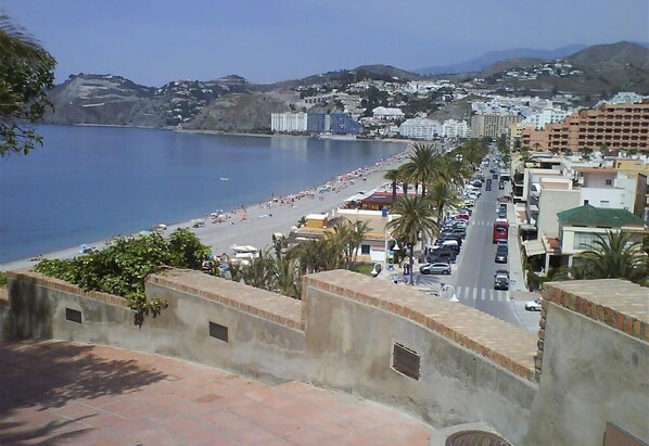A coastal cityscape with a beach, buildings, and a clear sky.