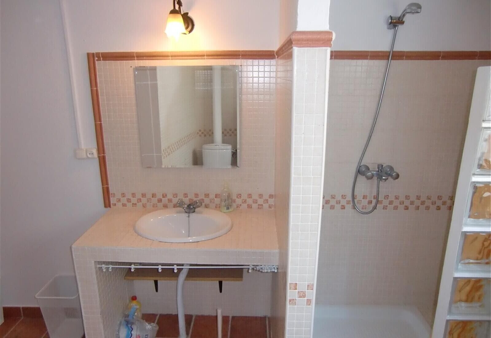 A bathroom with a sink, mirror, and shower.