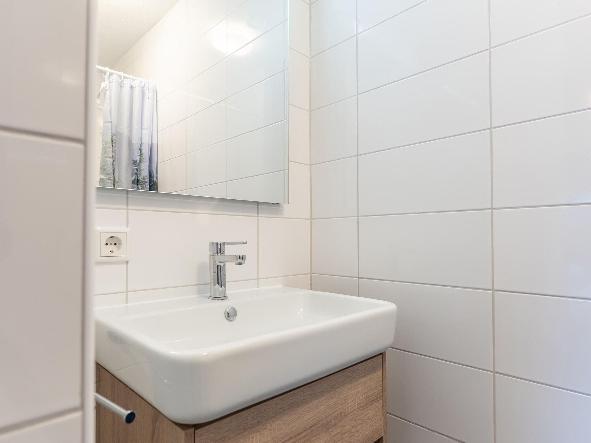 A bathroom with a white sink, a mirror, and a wooden cabinet.