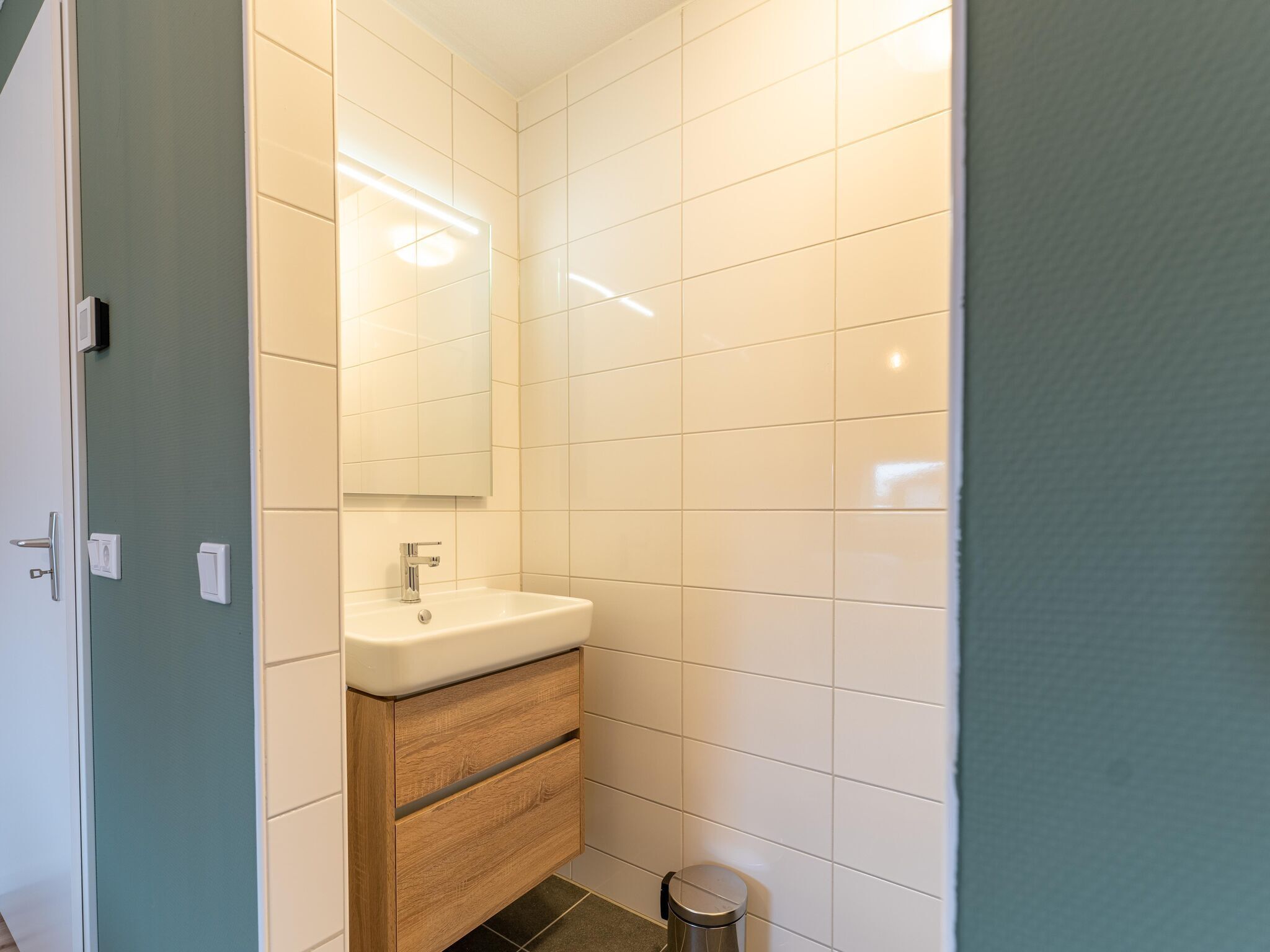 A bathroom with a white sink, a mirror, and a wooden cabinet.