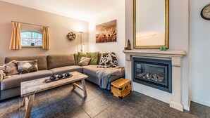 Una sala de estar con un sofá, una chimenea, un espejo y un cuadro.