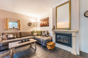 A living room with a sofa, a fireplace, a mirror, and a painting.