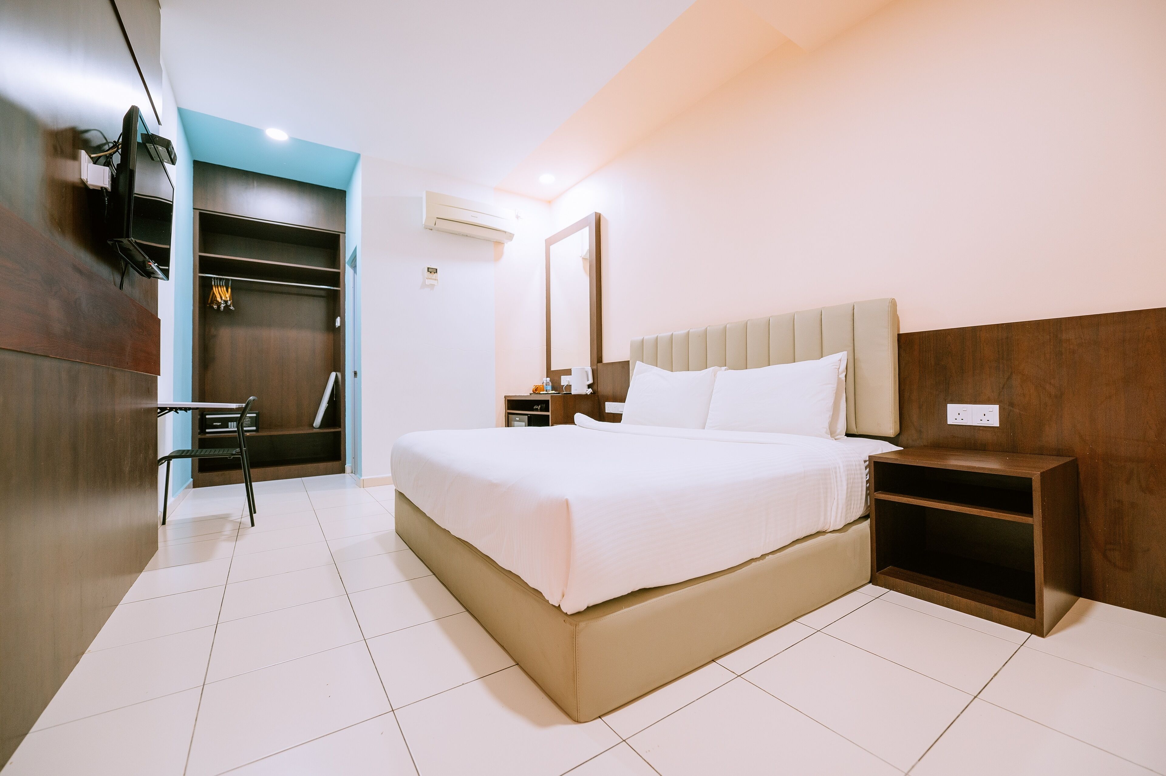 Een moderne hotelkamer met een groot bed, een nachtkastje, een kledingkast en een spiegel.