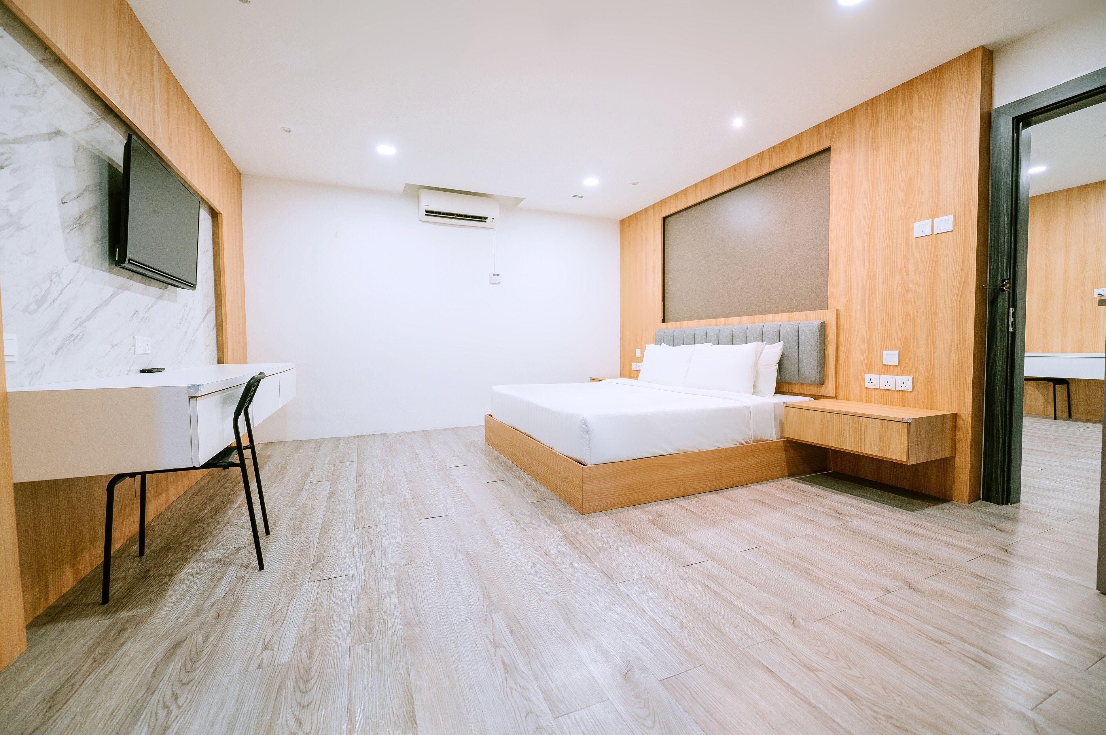 Una camera da letto moderna con un letto in legno, una scrivania e un televisore montato a parete.