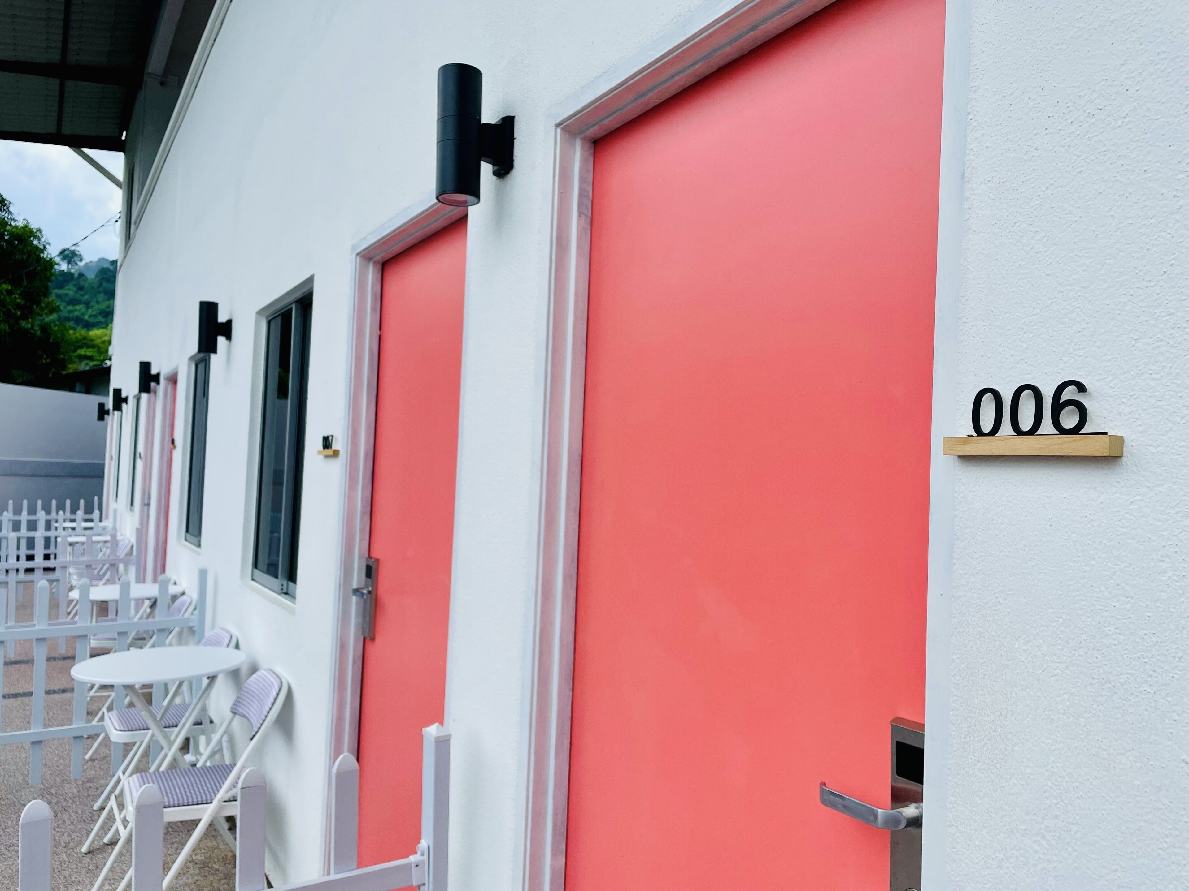 Un edificio con puertas rojas y una placa con el número '006' en la pared.