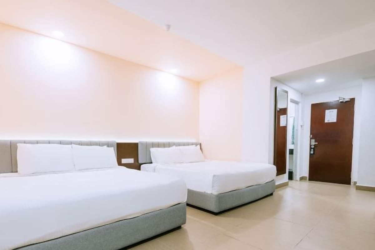 Une chambre d’hôtel avec deux lits, une porte en bois et un mur blanc.