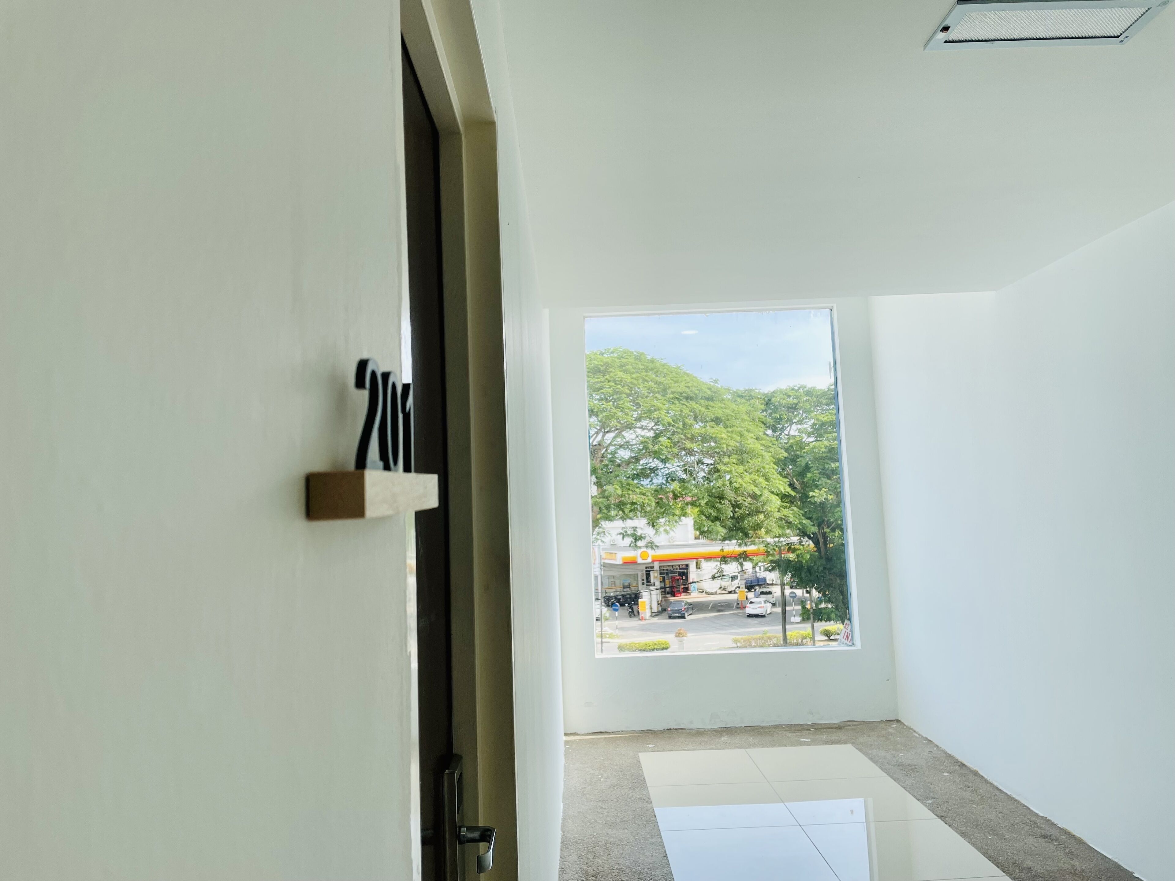 Una habitación con un ventanal grande, una puerta y un cartel con número en la pared.