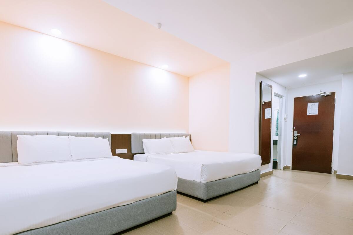 Ein Hotelzimmer mit zwei Betten, einer Holztür und einem Spiegel.