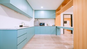 A modern kitchen with teal cabinetry, a wooden countertop, and a built-in microwave. - The Concept Hotel Langkawi (Langkawi)