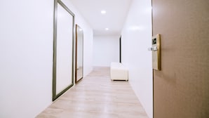 A modern hallway with a wooden floor, white walls, and a bench. - The Concept Hotel Langkawi (Langkawi)