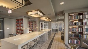 A modern library with a long white table, bookshelves, and a patterned wall. - Resort Style 2 bed/2bath Apartment in Spring, Tx (Spring)