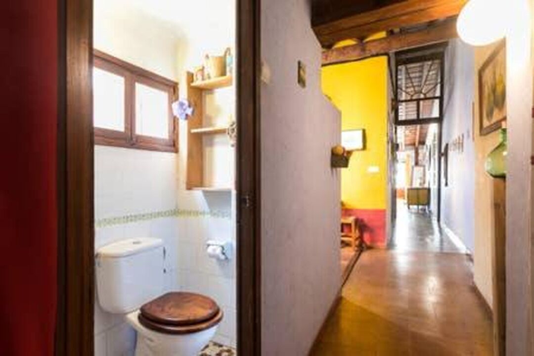 A narrow hallway leading to a bathroom with a toilet and a sink.