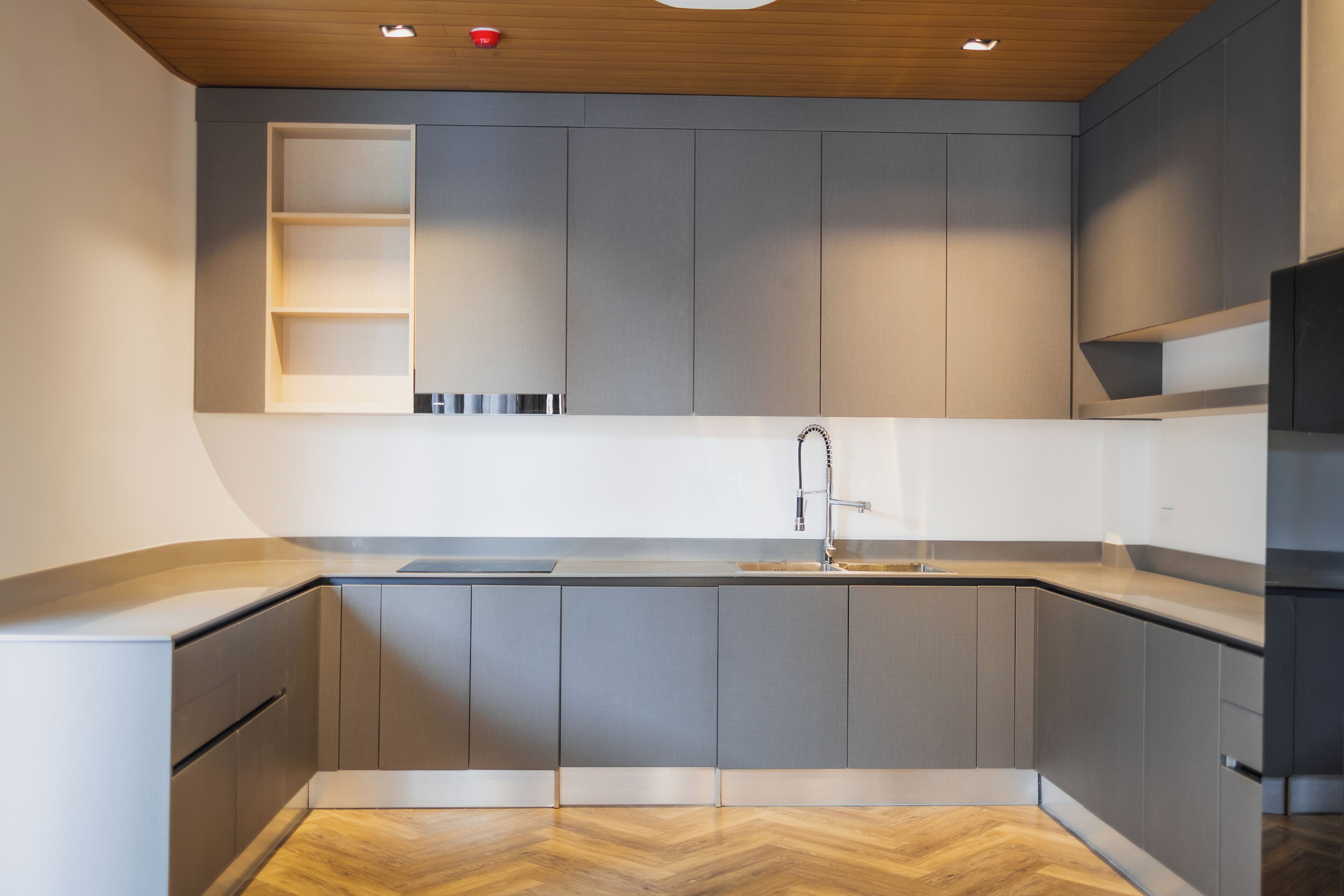 Una cocina moderna con armarios grises, encimera de madera y suelo con patrón de espiga.