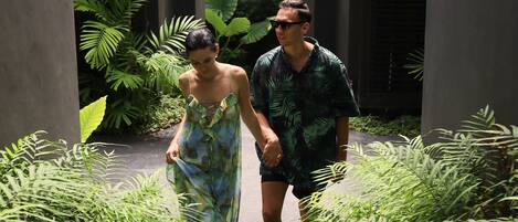 A couple walking through a modern building with a pathway surrounded by lush greenery.