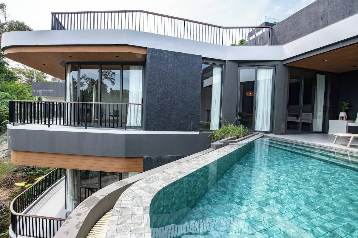 A modern house with a swimming pool, large windows, and a balcony.