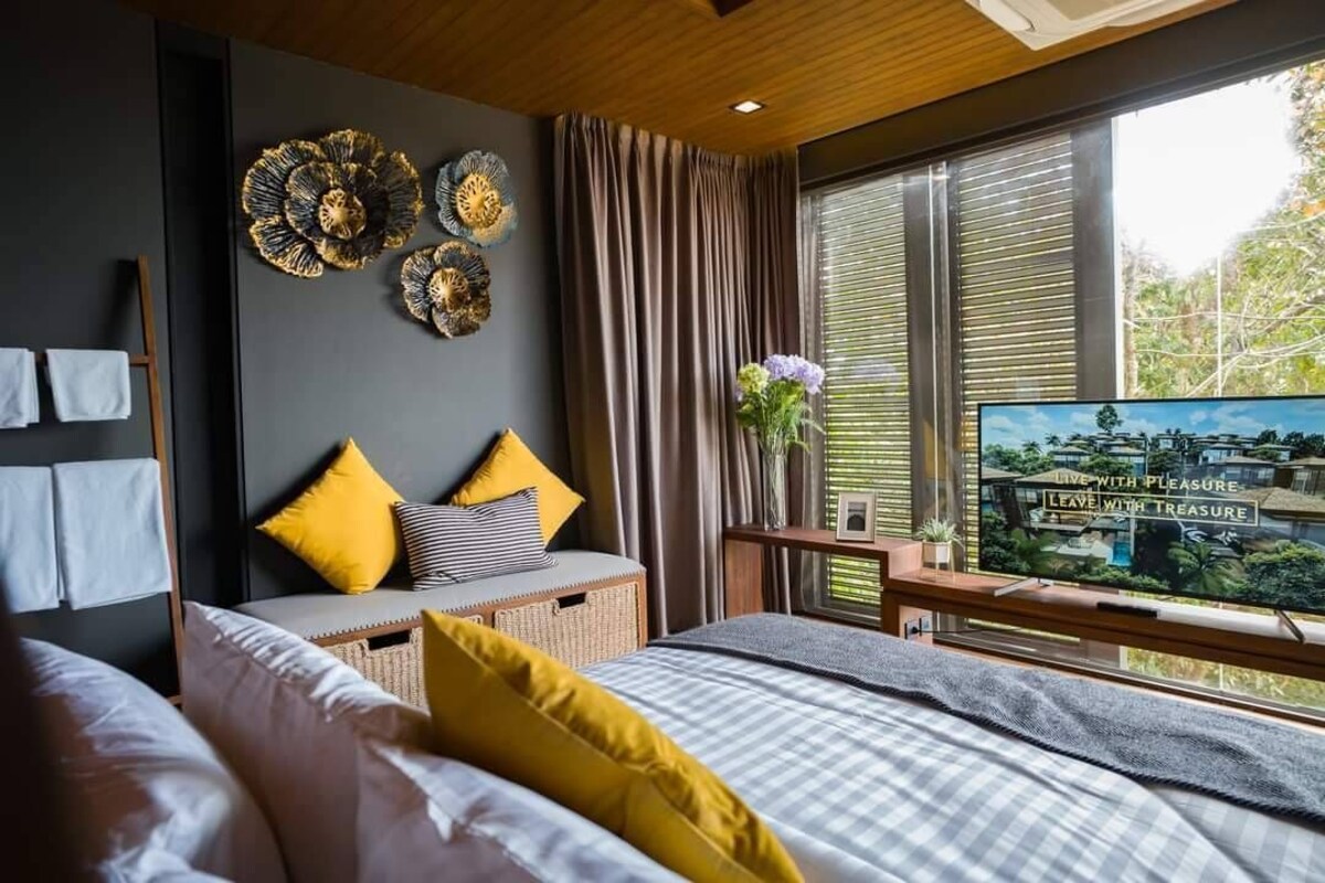 Un dormitorio moderno con cama, televisor y ventana con persianas.