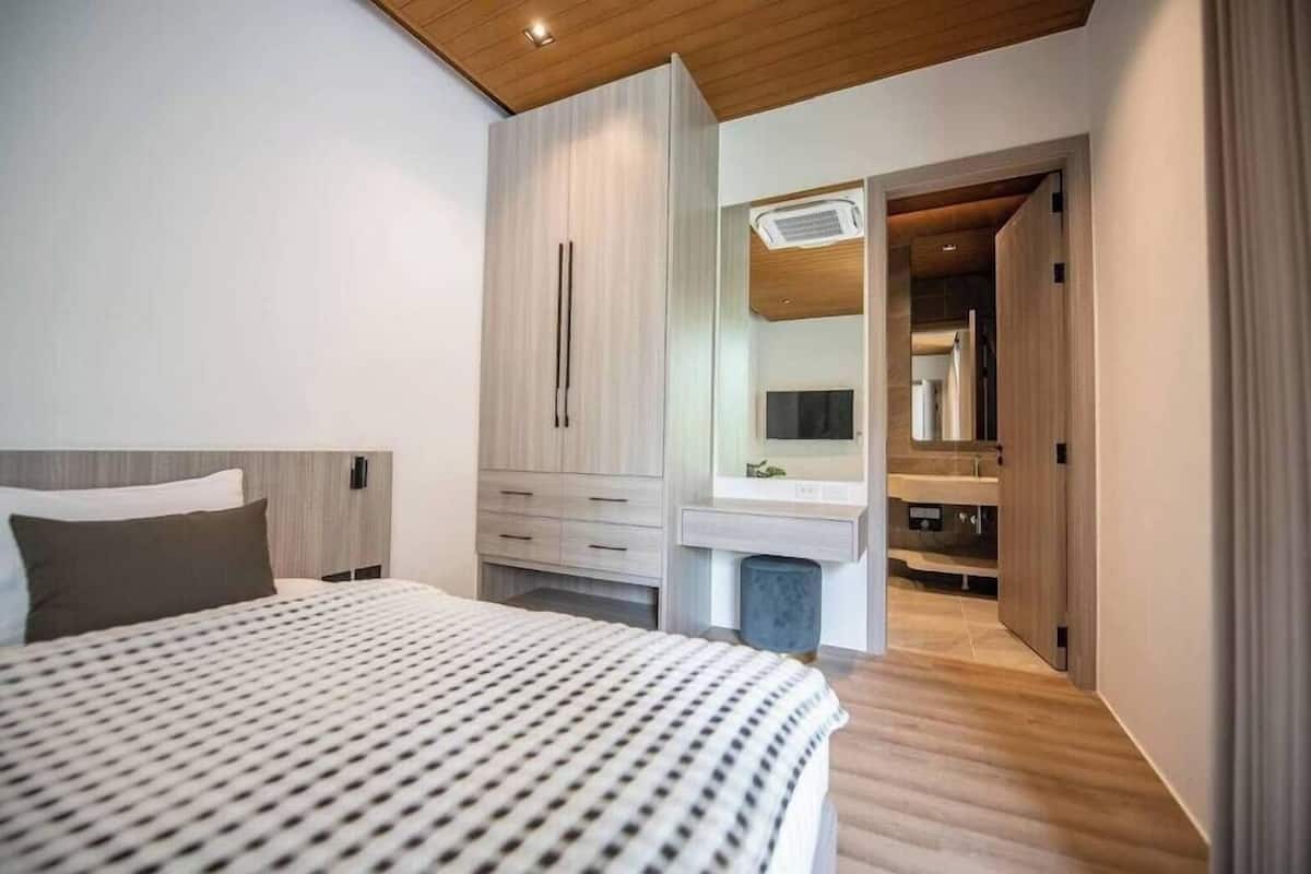 A modern bedroom with a bed, a wardrobe, a vanity with a mirror, and a walk-in closet.