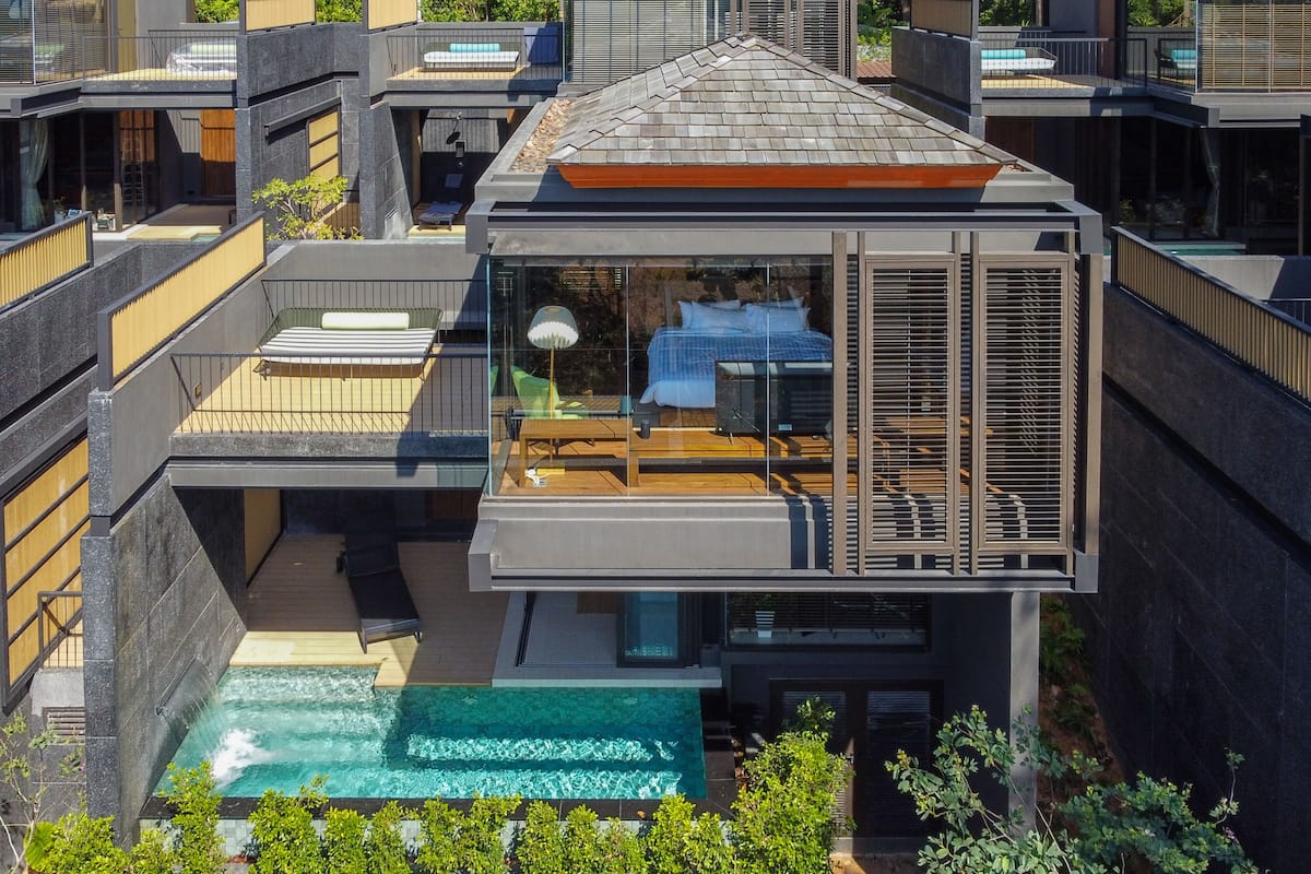 A modern multi-story building with a rooftop pool, outdoor seating, and a glass-enclosed balcony.