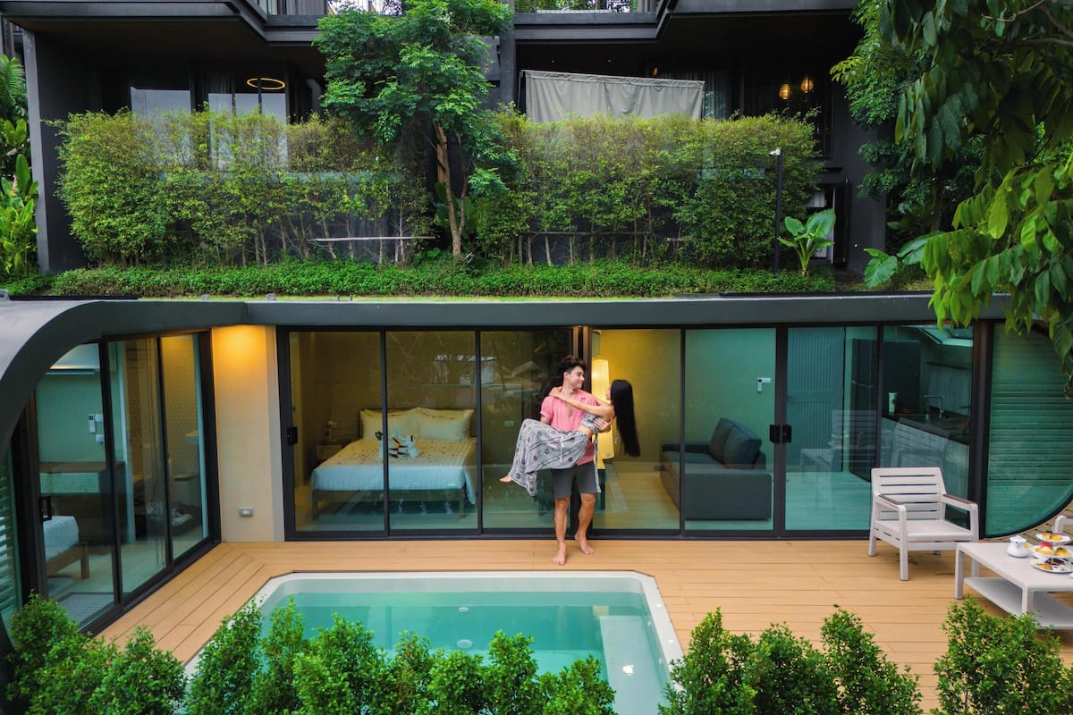 A modern villa with a glass-enclosed bedroom, a wooden deck, and a swimming pool.
