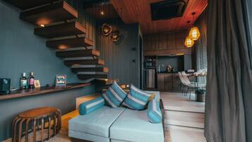 Una sala de estar moderna con un sofá, una escalera de madera, una zona de cocina y un comedor.