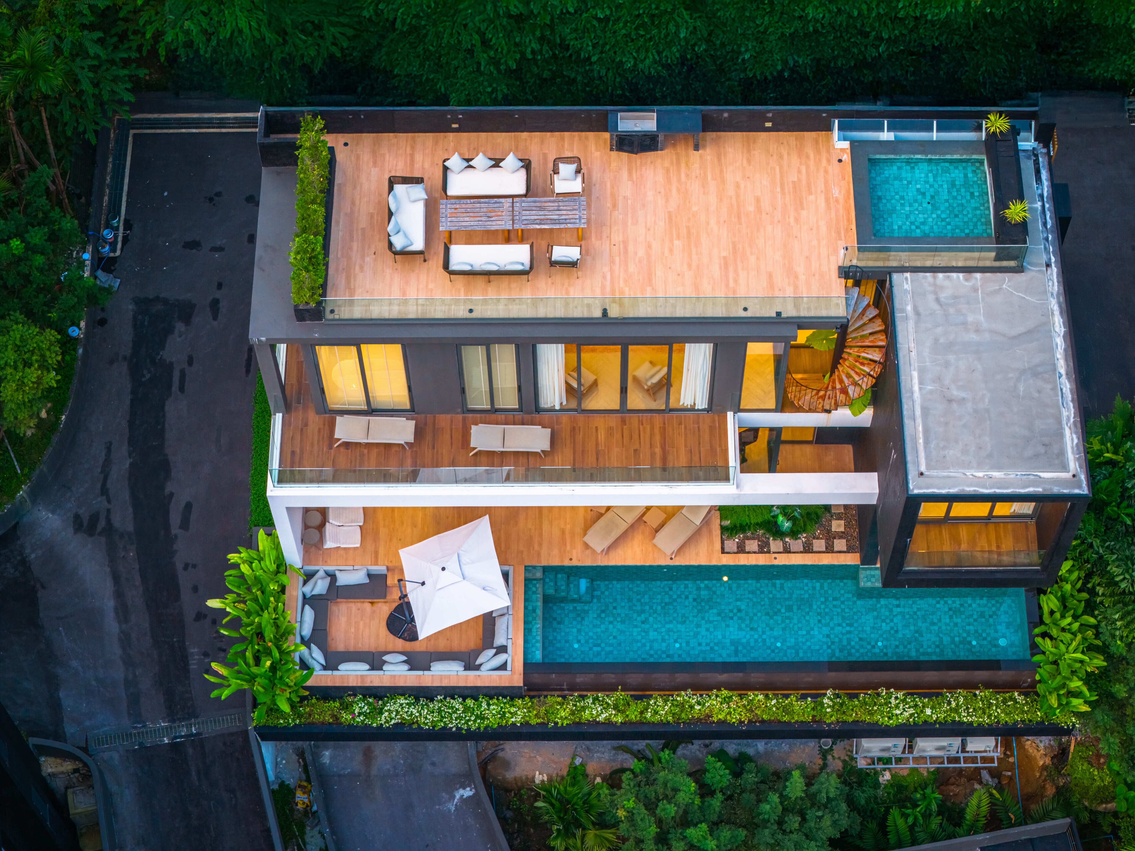 Una casa moderna de varios pisos con una terraza en la azotea, una piscina y una escalera espiral.