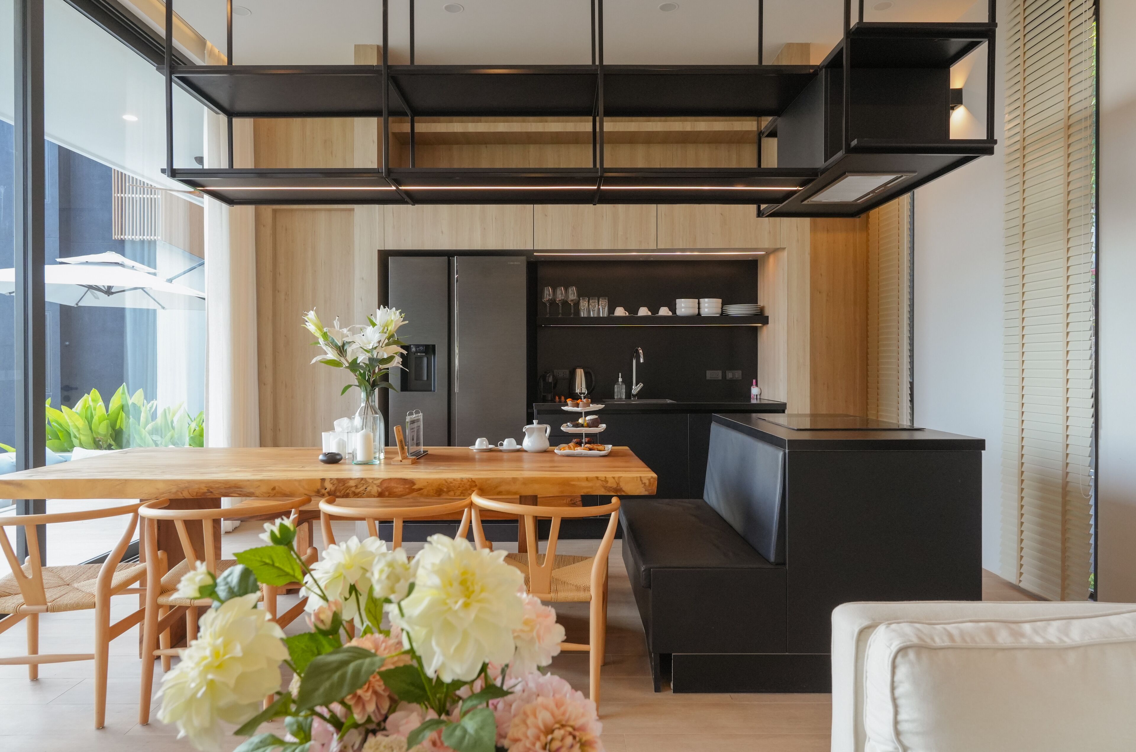A modern kitchen with a wooden dining table, black cabinets, and a built-in oven.