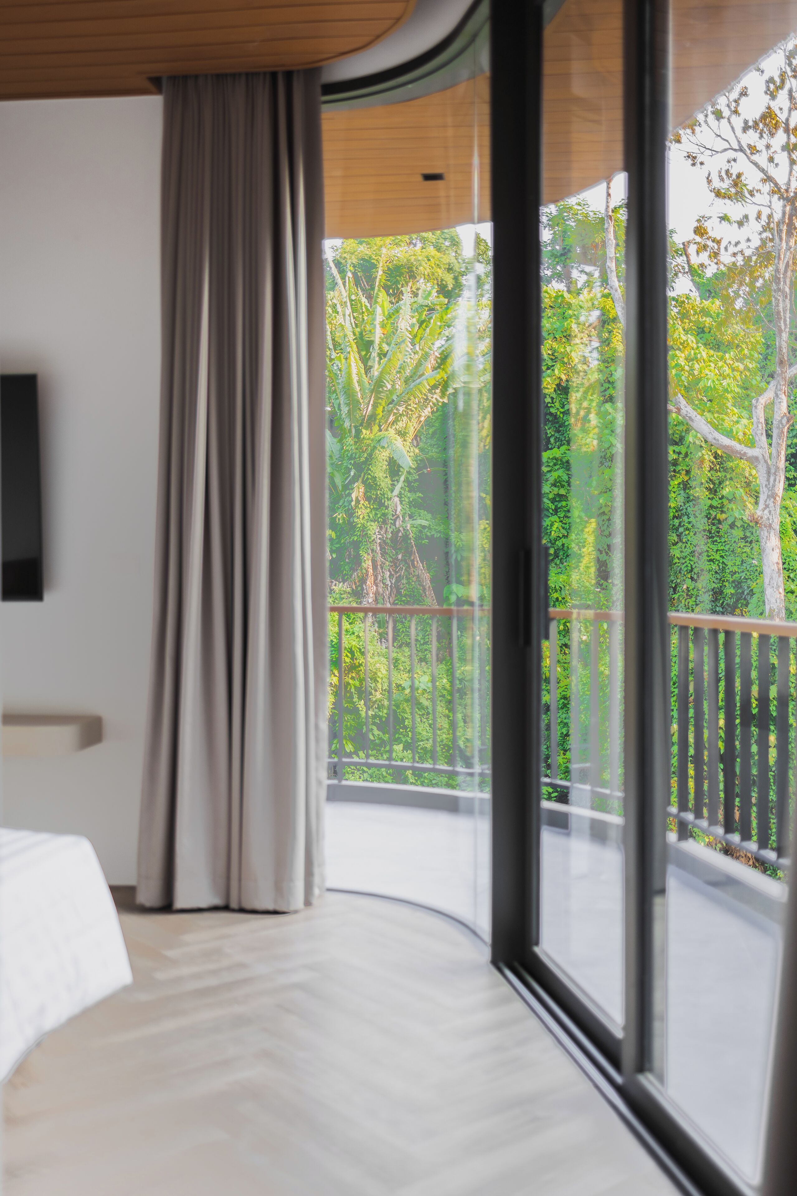 A modern hotel room with a large window, a bed, and a wooden ceiling.