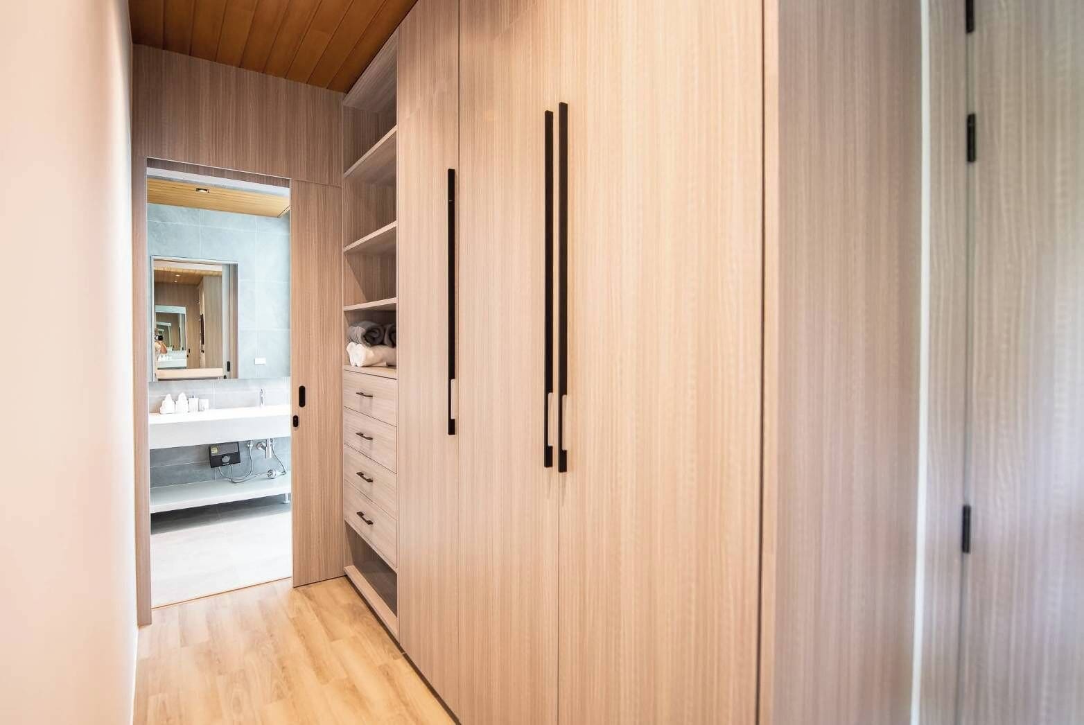 A modern bathroom with a wooden vanity, a mirror, and a towel rack.