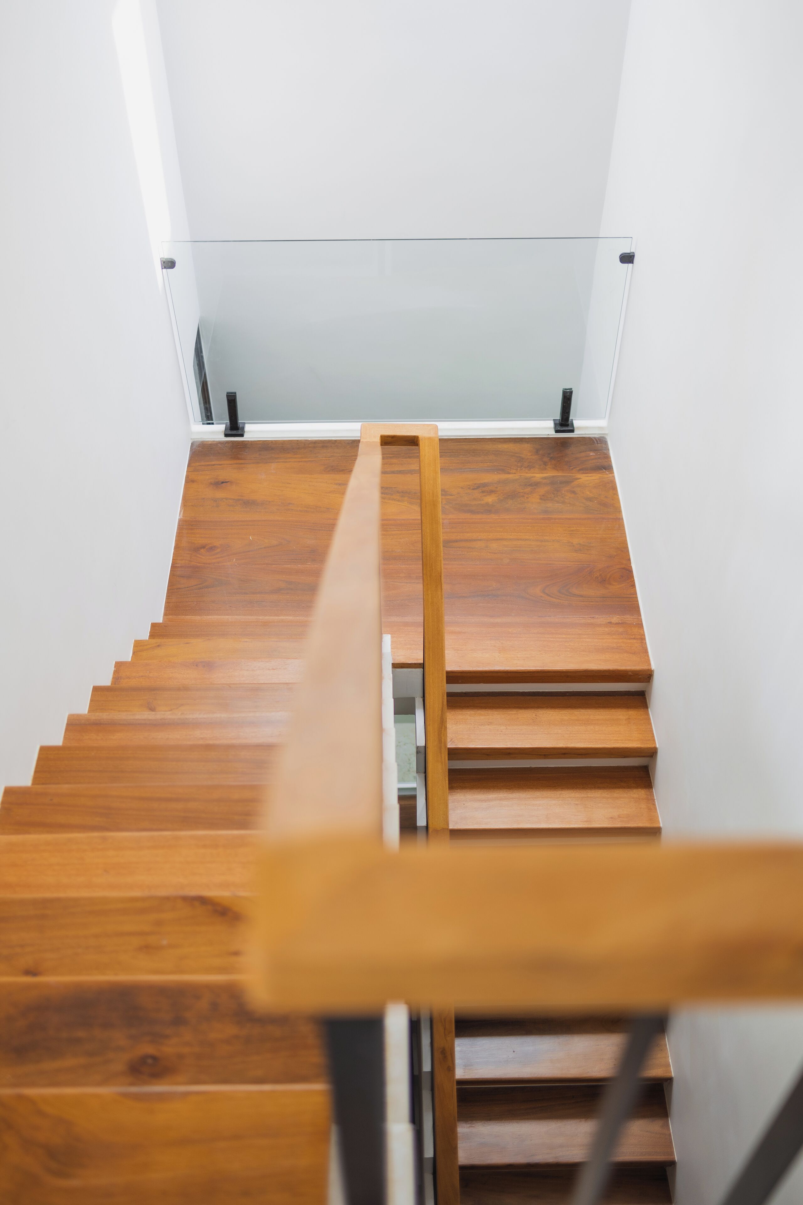 A wooden staircase with a glass railing and a wooden handrail.