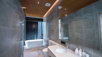A modern bathroom with a freestanding bathtub, a large mirror, and a vanity with a sink.