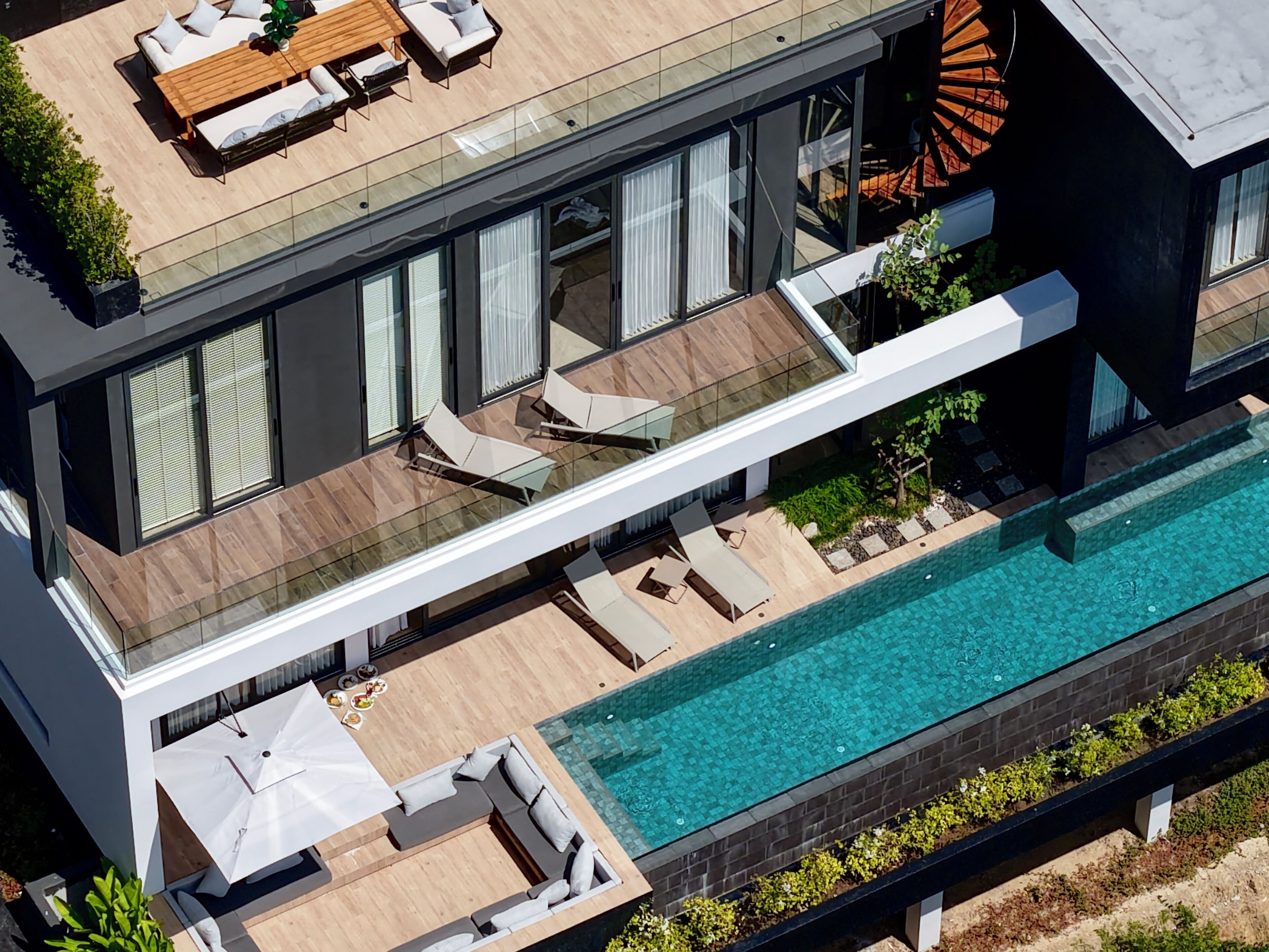 A modern house with a rooftop patio, a swimming pool, and a glass-enclosed balcony.