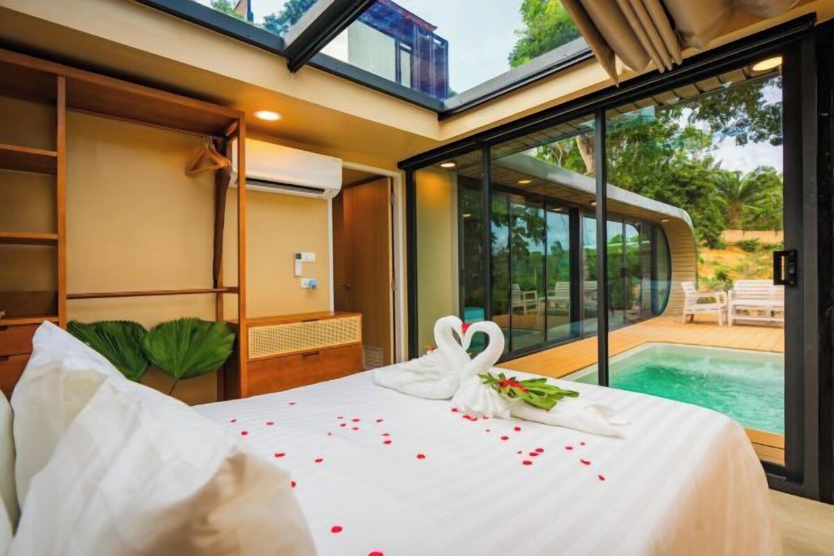 Habitación de hotel con cama, zona de ducha y vistas a una piscina.